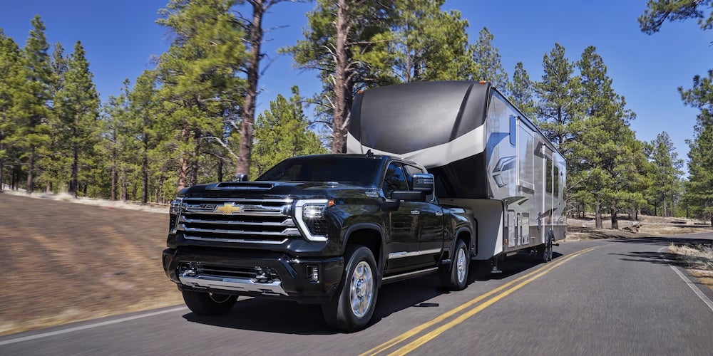A black 2026 Chevrolet Silverado HD towing an RV
