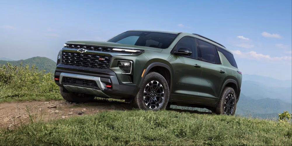 A green 2027 Chevrolet Traverse SUV cresting a grassy hill