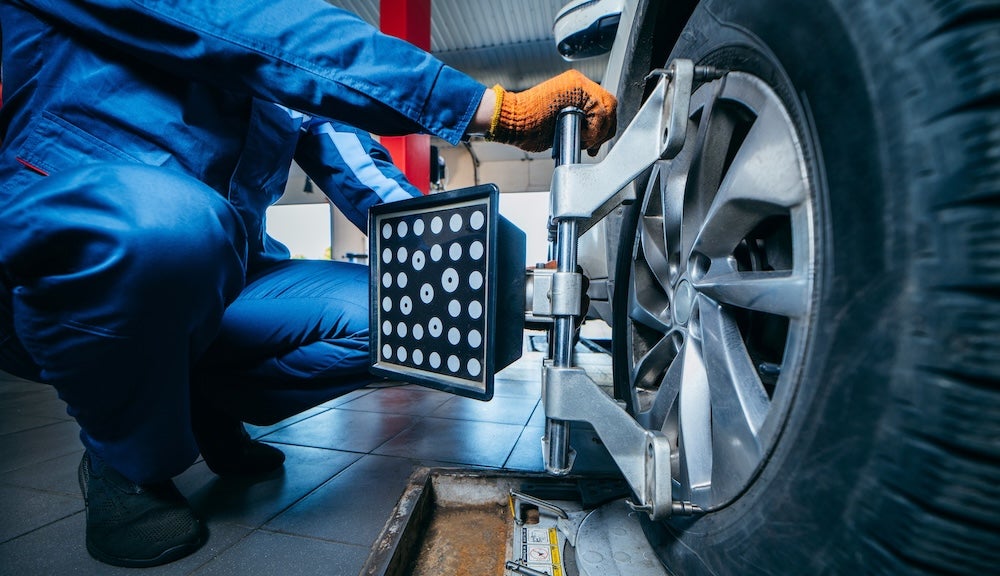 A service technician performing a wheel alignment on a vehicle