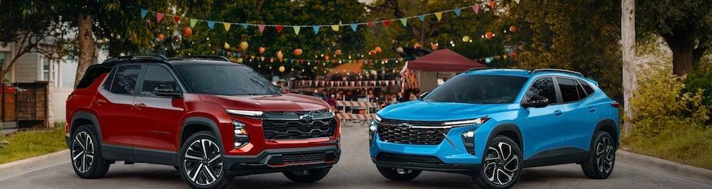 A red and a blue Chevrolet SUV parked in front of a block party