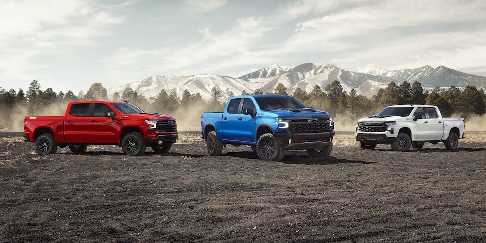 Three Chevrolet pickup trucks parked on a dirt field