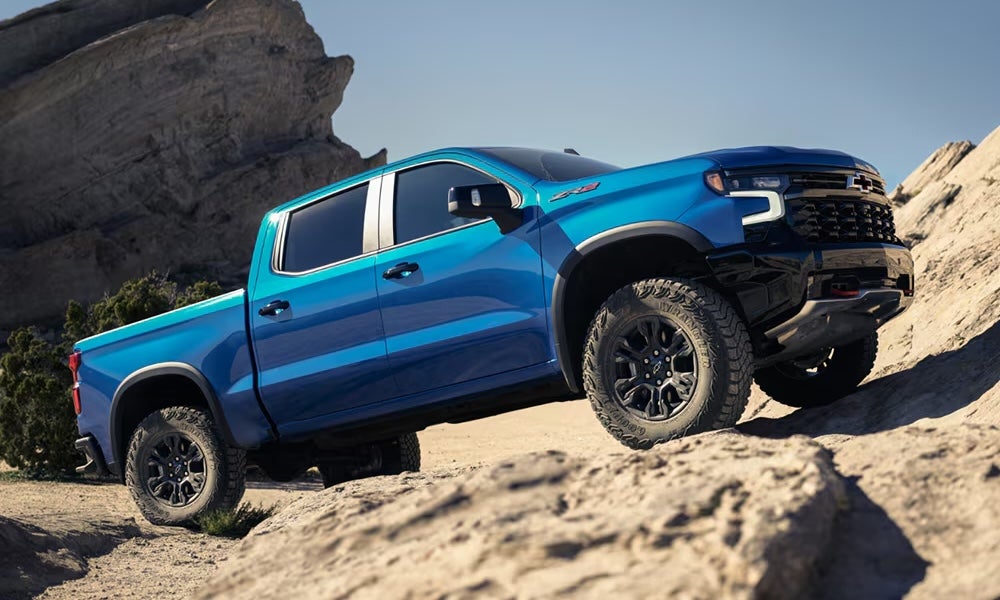 A bright blue 2026 Chevrolet Silverado pickup truck parked on rocks